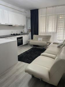 ein Wohnzimmer mit weißen Möbeln und eine Küche in der Unterkunft Relaxing and Beautiful Apartments in Centre of Historical Suceava in Suceava