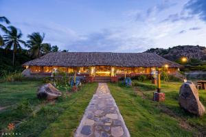 una casa con techo de paja con un camino que conduce a ella en Zostel Hampi (Gangavathi), en Hampi