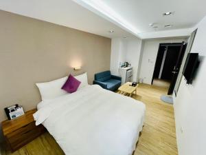 森浩文旅 في تايبيه: غرفة نوم بسرير ابيض كبير وكرسي ازرق