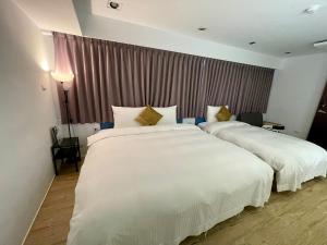 2 camas en una habitación de hotel con sábanas blancas en 森浩文旅 en Taipéi