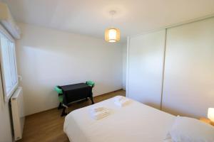 - une chambre avec un lit blanc et une chaise dans l'établissement Le Discret T2 aux portes de la vieille ville, à Annecy