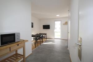 a living room with a television and a table with chairs at MOWO Marshall 8 - Apartmenthaus Kitzingen - großzügige Wohnungen für je 6 Personen mit Balkon in Kitzingen