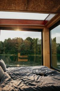 uma cama num quarto com uma grande janela em AQUACHILL houseboat & wellness em Liptovský Trnovec