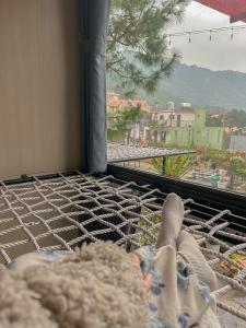 a person laying on a hammock looking out a window at Bách Xanh House Venuestay in Vĩnh Phúc