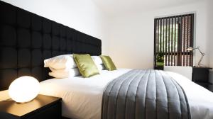 a bed with a white comforter and pillows at Andora Apartments in London