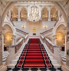 una scala rossa in moquette in un edificio con lampadario a braccio di Raffles London at The OWO a Londra