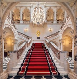a red carpeted staircase in a building with a chandelier at Raffles London at The OWO in London