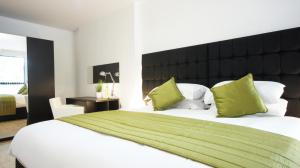 a bedroom with a large white bed with green pillows at Andora Apartments in London