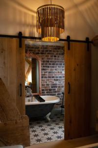 a bathroom with a bath tub and a chandelier at The Cart House - Beautiful Contemporary Barn - Hot Tub in Bridgnorth +33 photos