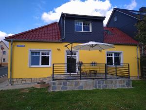 ein gelbes Haus mit einem Tisch und einem Regenschirm in der Unterkunft Ferienhaus Opolka in Balgstädt