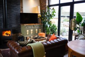 sala de estar con sofá de cuero y chimenea en The Cart House - Beautiful Contemporary Barn - Hot Tub, en Bridgnorth