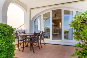 um pátio com uma mesa e cadeiras numa varanda em White Sands Beach Club em Arenal d'en Castell