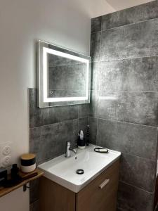 La salle de bains est pourvue d'un lavabo et d'un miroir. dans l'établissement Appartement Confortable et Spacieux Boulogne-Billancourt, à Boulogne-Billancourt