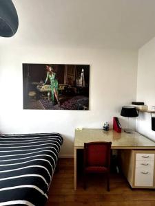 - une chambre avec un lit et un bureau avec une photo sur le mur dans l'établissement Appartement Confortable et Spacieux Boulogne-Billancourt, à Boulogne-Billancourt