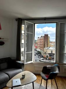 - un salon avec un canapé et une grande fenêtre dans l'établissement Appartement Confortable et Spacieux Boulogne-Billancourt, à Boulogne-Billancourt