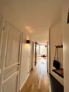 - un couloir avec une porte blanche et du parquet dans l'établissement Appartement Confortable et Spacieux Boulogne-Billancourt, à Boulogne-Billancourt