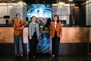 a group of three women standing in front of a counter at MUU Bangkok Hotel in Bangkok