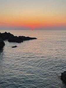 een zonsondergang boven de oceaan met rotsen in het water bij Ambra in Stazzo