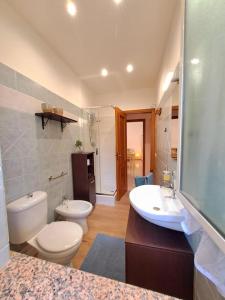 een badkamer met 2 toiletten, een wastafel en een bad bij Ambra in Stazzo