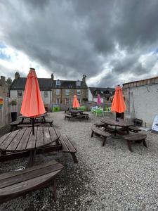 een groep picknicktafels met oranje paraplu's erop bij St Duthus Hotel Apartment in Tain