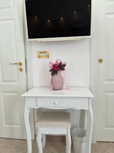 a pink vase on a white desk with a tv on it at B&B Euthalia in Riposto