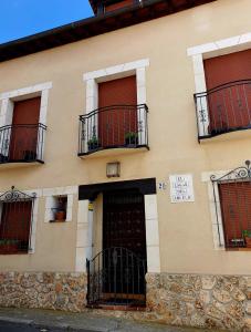 un edificio con balcones y una puerta con un cartel. en El lagar de Lolo, en Hontanares de Eresma