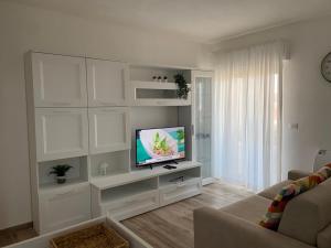 uma sala de estar com televisão num quarto branco em La maison du mar em Bari