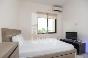 a white bedroom with a bed and a window at RedLiving Apartemen RQ at Ecohome Citra Raya in Nalagat