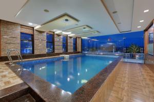 a large swimming pool with blue water in a building at Click Hotel Sagar Plaza Chakan, Pune in Chakan