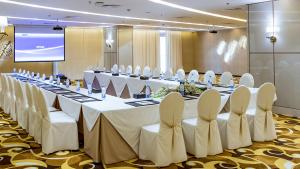 a conference room with a long table with chairs and a screen at M Hotel Makkah by Millennium in Mecca