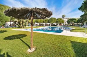 un ombrellone nell'erba accanto a una piscina di Carrajolilla Sancti petri a Chiclana de la Frontera