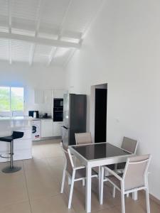 una cucina con tavolo, sedie e frigorifero di Ruddy’s house a Le Gosier