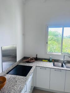 a white kitchen with a sink and a window at Ruddy’s house in Le Gosier