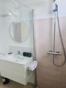 ein Bad mit einem Waschbecken und einer Dusche mit einem Spiegel in der Unterkunft Ruddy’s house in Le Gosier