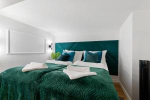 a green bed with white and blue pillows on it at Tempus Te Premium Duo Lofts Tartu - private cinema, gym and terrace in Tartu