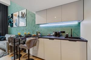 a kitchen with white cabinets and a table with chairs at Tempus Te Premium Duo Lofts Tartu - private cinema, gym and terrace in Tartu