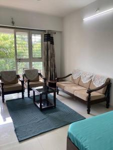een woonkamer met een bank, stoelen en een tafel bij Secluded Serenity in Central Pune:Your Second home in Pune