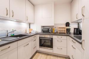 eine Küche mit weißen Schränken, einer Spüle und einer Mikrowelle in der Unterkunft Förde-Lodge in Glücksburg