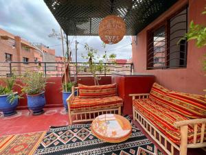 eine Terrasse mit einem Sofa und Stühlen auf dem Balkon in der Unterkunft Marrakech Mirage Home in Marrakesch