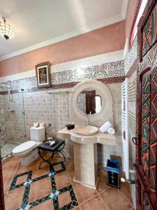 a bathroom with a sink and a toilet and a mirror at Riad Clé De Sol in El Jemʼa Ghemat