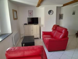 ein Wohnzimmer mit 2 roten Stühlen und einem TV in der Unterkunft Gîte Linglet in Fumay