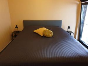 Una cama con una almohada amarilla encima. en Het Zonnetje -Vakantiewoning en Bed and Breakfast, en Dilsen-Stokkem
