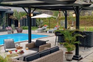 a patio with chairs and an umbrella and a pool at LohonoStays Uday Villa in Waki