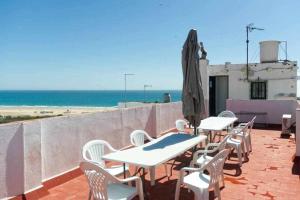 uma fileira de mesas e cadeiras com um guarda-sol e a praia em Apartamento Venus Conil em Conil de la Frontera