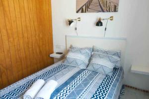 uma cama com lençóis e almofadas azuis e brancos em Apartamento Venus Conil em Conil de la Frontera