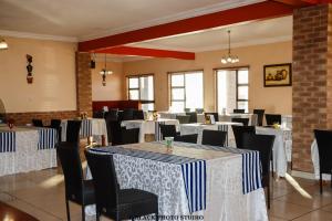 a dining room with tables and chairs with white and blue linens at Meet Mekaar Resorts - Nquthu Hotel in Nqutu