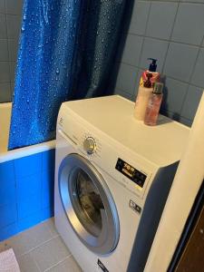 a washing machine in a bathroom with a blue shower curtain at ShortStopPasilaiciai in Vilnius