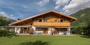 a large wooden house with a balcony in the mountains at Haus Barbara in Bach
