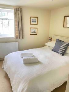 sypialnia z białym łóżkiem i 2 ręcznikami w obiekcie High end cottage in amazing location. Only 1 minute from the sea! Beautifully decorated 3 level home. 5* reviews w mieście Lyme Regis