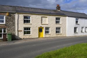 a stone house with a yellow door on a street at April Cottage in Saint Just in Roseland